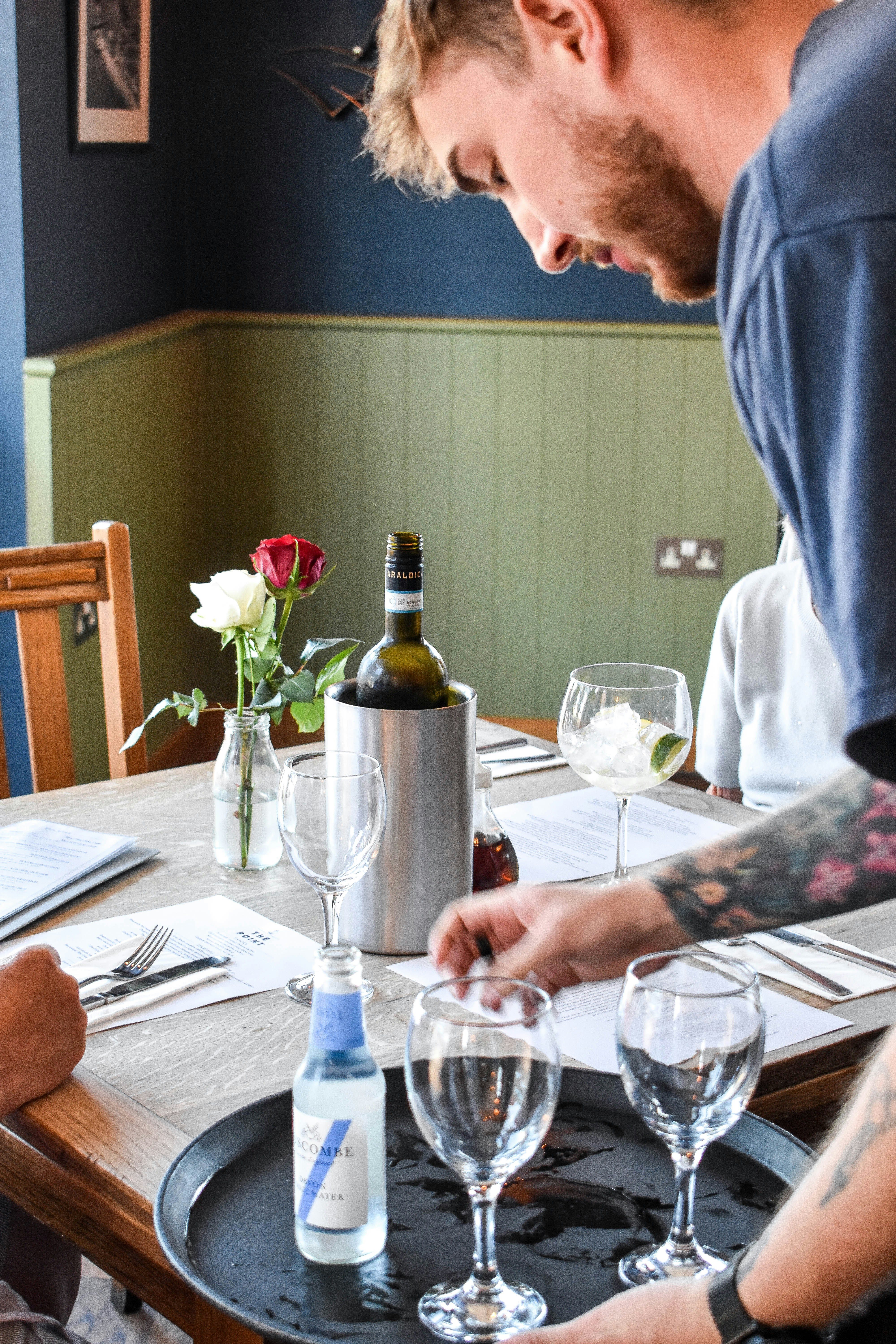Professional server confidently presenting wine to customers, demonstrating expert upselling techniques and beverage service